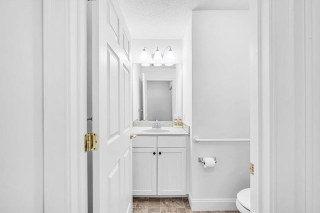 bathroom featuring a textured ceiling, vanity, and toilet