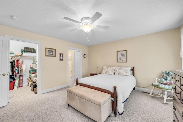 carpeted bedroom featuring ceiling fan, a spacious closet, a textured ceiling, and a closet