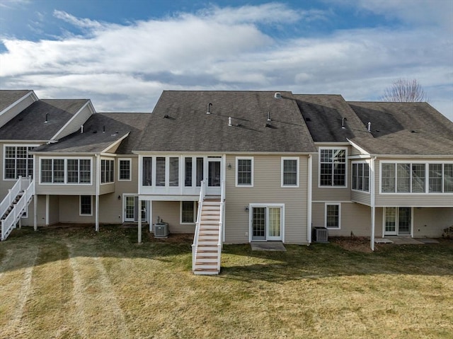 rear view of property with a sunroom, a yard, and central AC unit