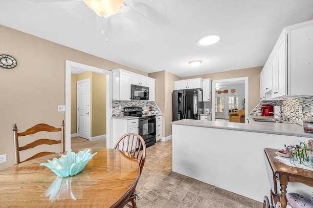 kitchen featuring kitchen peninsula, backsplash, sink, black appliances, and white cabinets