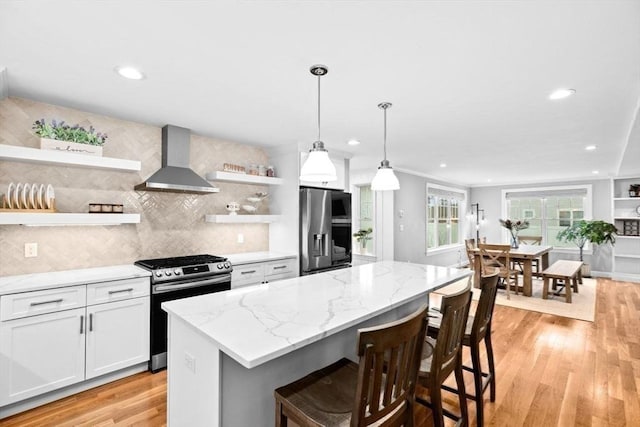 kitchen featuring wall chimney exhaust hood, stainless steel appliances, open shelves, and light wood-type flooring