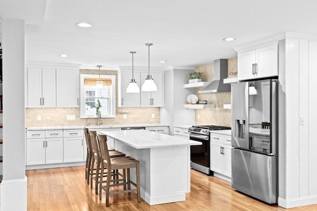 kitchen featuring white cabinetry, stainless steel appliances, and wall chimney exhaust hood