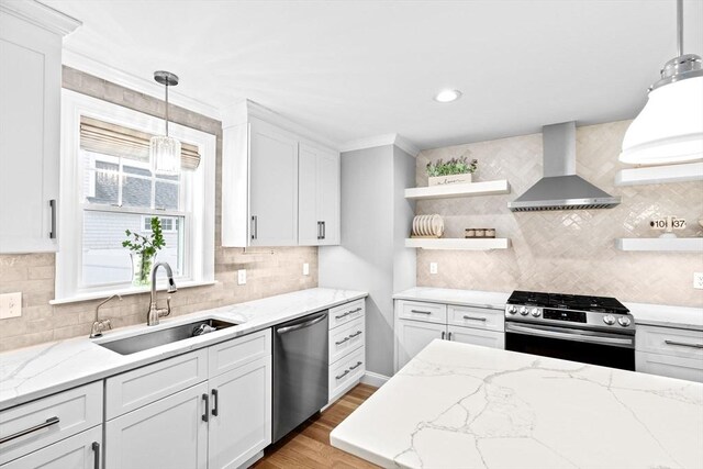kitchen with a sink, open shelves, wall chimney exhaust hood, appliances with stainless steel finishes, and white cabinets
