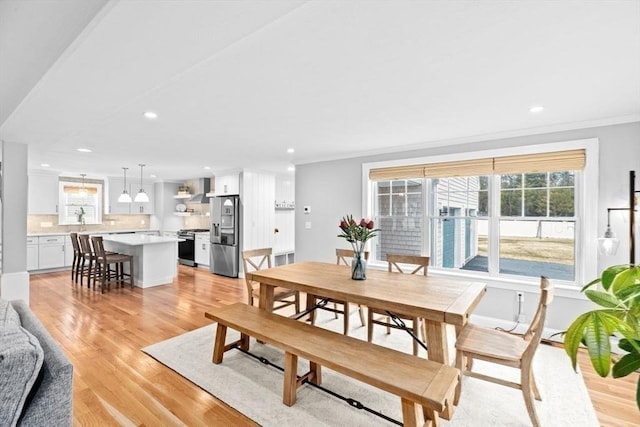 dining space featuring light wood-style flooring, crown molding, baseboards, and recessed lighting