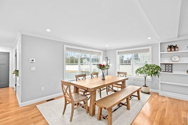 dining area featuring baseboards, visible vents, crown molding, and light wood-type flooring
