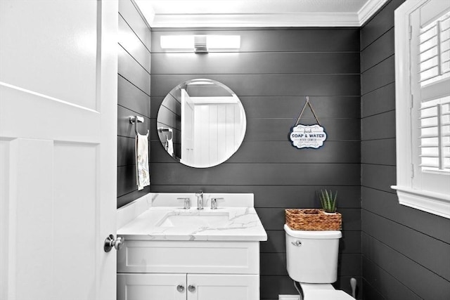 bathroom featuring toilet, ornamental molding, and vanity