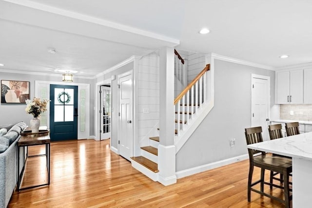 entrance foyer featuring light wood finished floors, stairs, baseboards, and ornamental molding