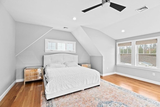 bedroom with baseboards, visible vents, vaulted ceiling, and wood finished floors