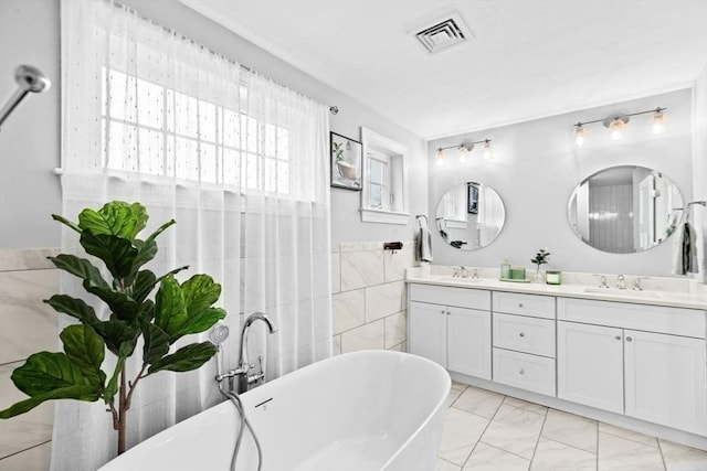 full bathroom featuring a freestanding tub, a sink, marble finish floor, visible vents, and double vanity