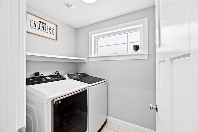 clothes washing area with independent washer and dryer, laundry area, baseboards, and light tile patterned floors
