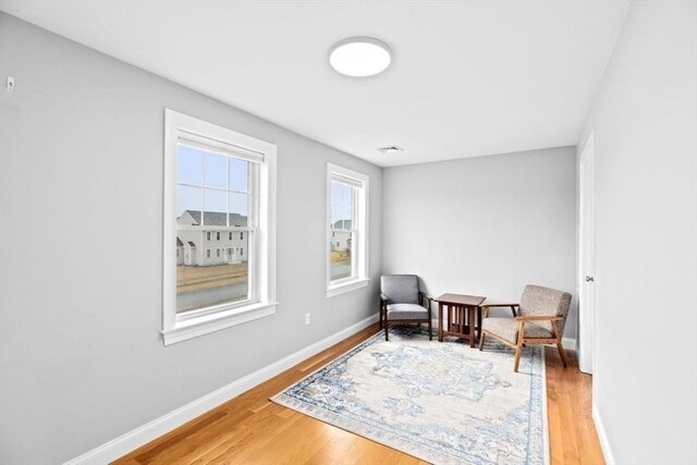 sitting room with baseboards, visible vents, and light wood-type flooring