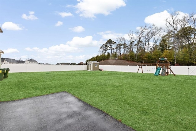 view of yard featuring an outdoor structure, a patio, a fenced backyard, playground community, and a storage shed