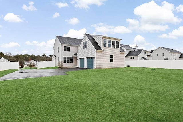 rear view of property featuring a yard, aphalt driveway, fence, and an attached garage
