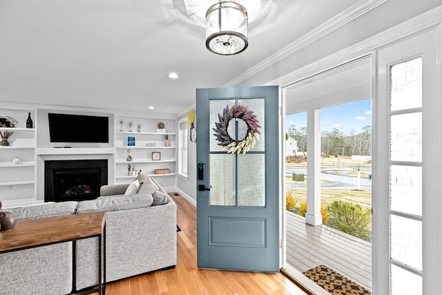 entryway featuring a fireplace, recessed lighting, crown molding, and light wood finished floors