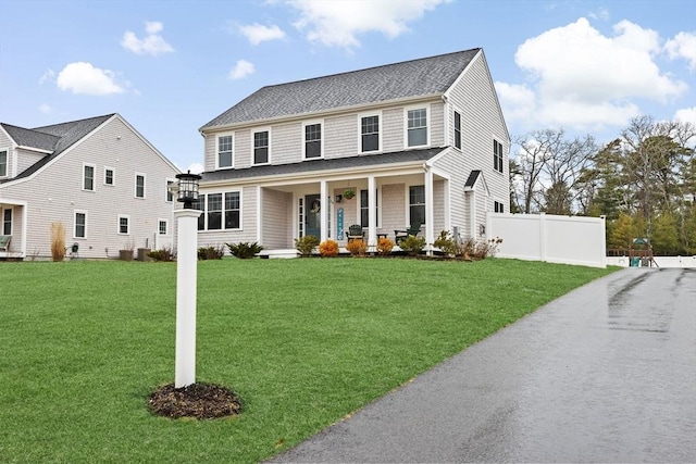 view of front of home featuring a front yard, fence, a shingled roof, a porch, and central AC