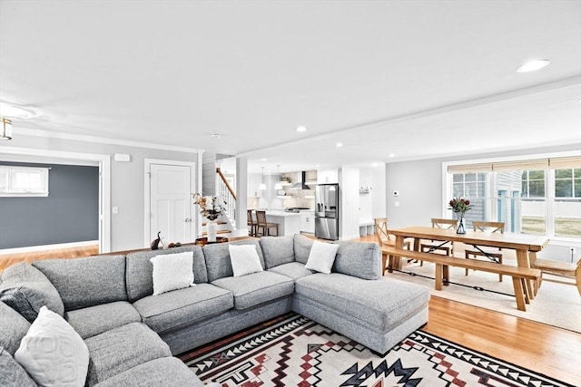 living area featuring crown molding, stairway, baseboards, light wood-style floors, and recessed lighting