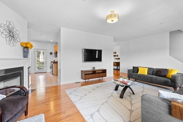 living room featuring light wood-style floors and a glass covered fireplace