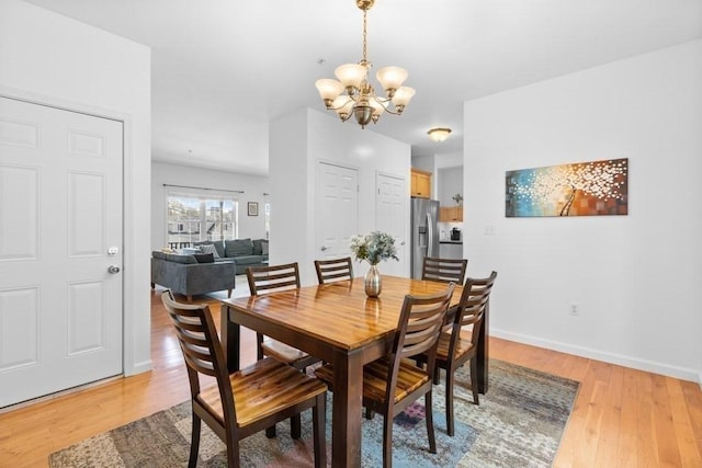 dining room with baseboards, light wood-style flooring, and a notable chandelier