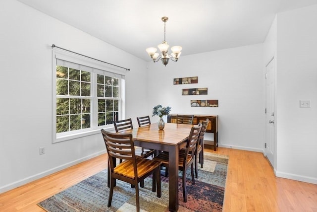 dining room featuring light wood-style floors, baseboards, and a notable chandelier