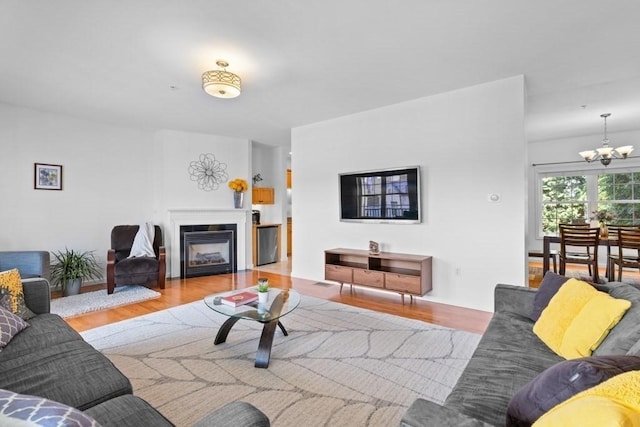 living area featuring a chandelier, a glass covered fireplace, and wood finished floors