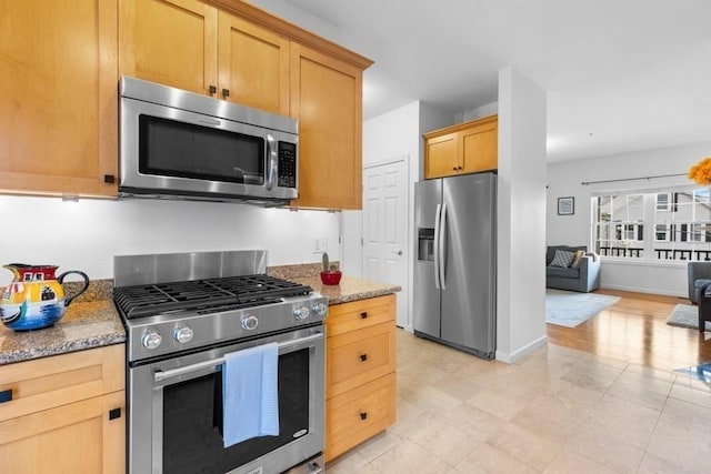 kitchen with light stone counters, open floor plan, and appliances with stainless steel finishes