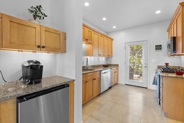 kitchen with stainless steel appliances, recessed lighting, stone counters, and a sink