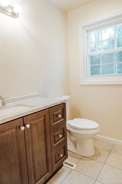 half bath with vanity, visible vents, baseboards, tile patterned floors, and toilet