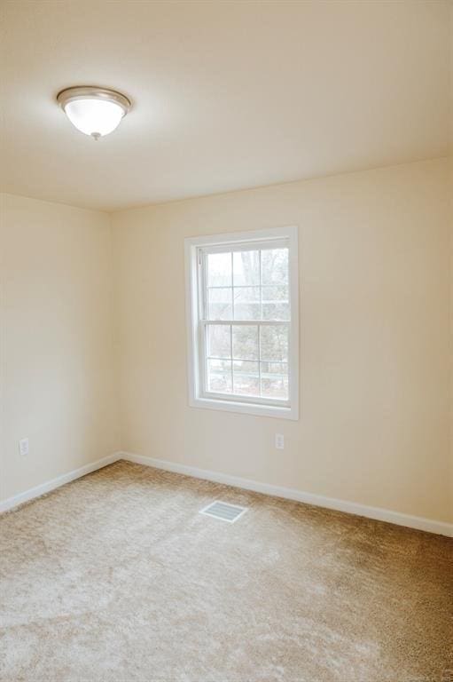 carpeted spare room featuring baseboards and visible vents