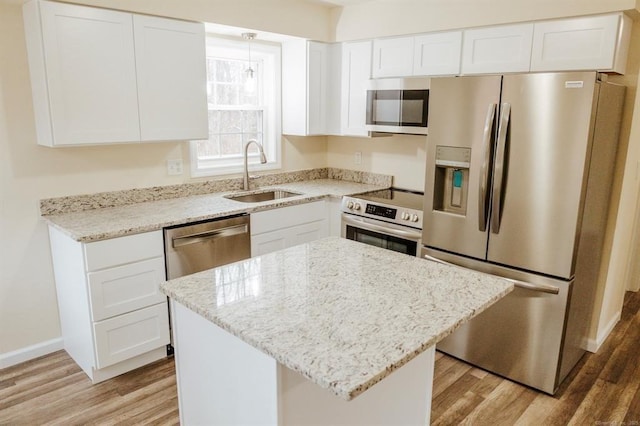 kitchen with light stone counters, a sink, stainless steel appliances, white cabinetry, and light wood-type flooring