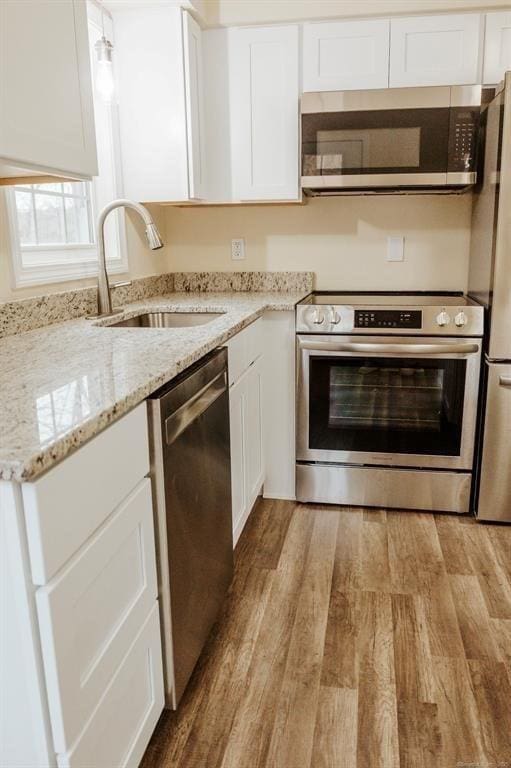 kitchen featuring a sink, stainless steel appliances, white cabinets, and light wood finished floors