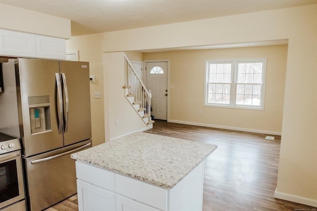 kitchen with white cabinetry, appliances with stainless steel finishes, a center island, and light wood-style floors