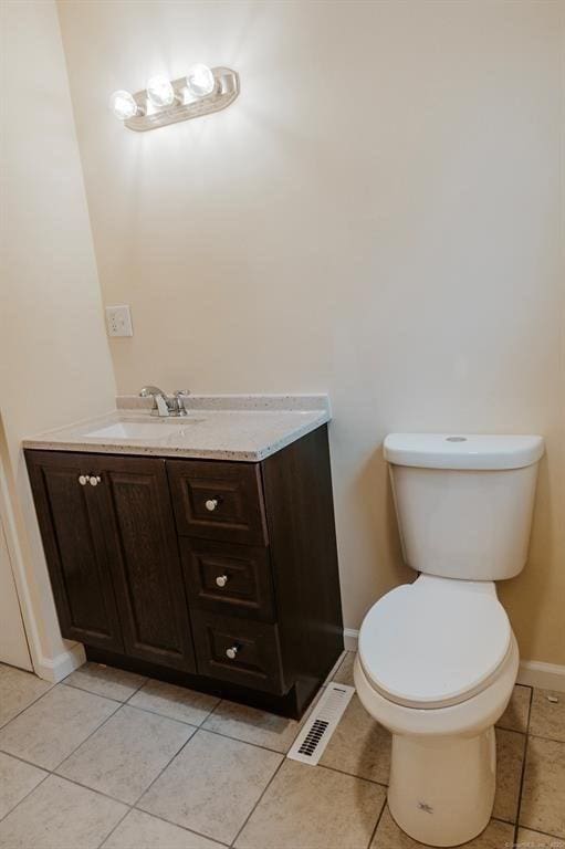 half bathroom with vanity, visible vents, baseboards, tile patterned flooring, and toilet