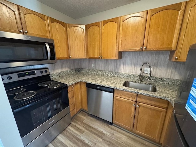 1186 Worcester Rd Unit 231, Framingham, MA 01702 - kitchen with stainless steel appliances, a sink, light wood-style flooring, light stone countertops, and a textured ceiling