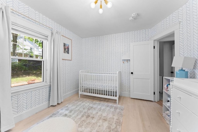 633 Lagrange St, Boston, MA 02132 - bedroom with wallpapered walls, light wood-type flooring, a crib, and baseboards