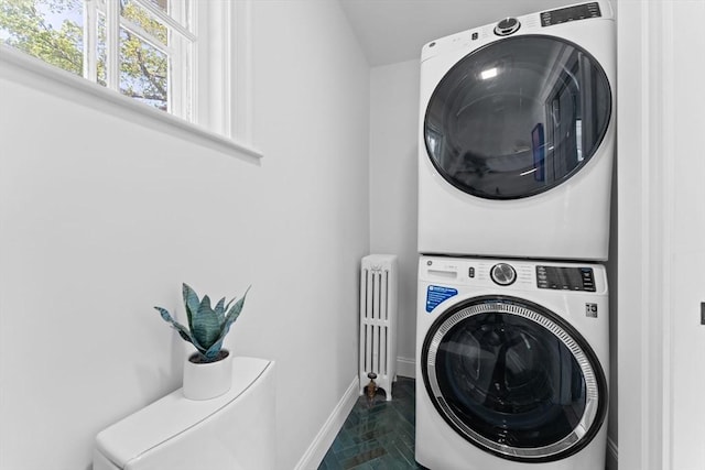 633 Lagrange St, Boston, MA 02132 - clothes washing area featuring stacked washing machine and dryer, radiator heating unit, and baseboards