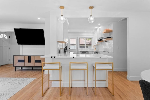 633 Lagrange St, Boston, MA 02132 - kitchen featuring white cabinets, a peninsula, a breakfast bar, light wood-style floors, and recessed lighting