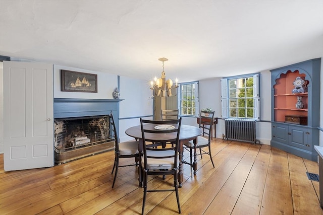 6 Lee St, Marblehead, MA 01945 - dining area featuring radiator heating unit, light wood finished floors, a fireplace, and a chandelier