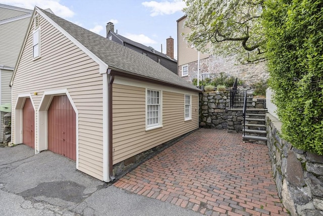 6 Lee St, Marblehead, MA 01945 - view of side of property featuring stairway, a shingled roof, a chimney, a patio area, and a garage