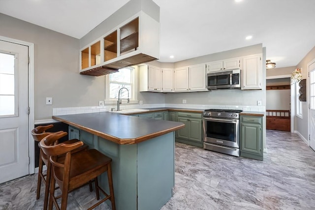 kitchen with sink, white cabinetry, appliances with stainless steel finishes, kitchen peninsula, and green cabinets