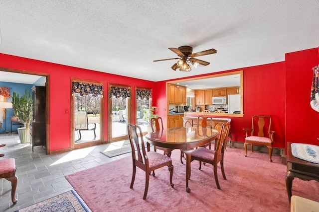dining space with a baseboard radiator, baseboards, a ceiling fan, and a textured ceiling