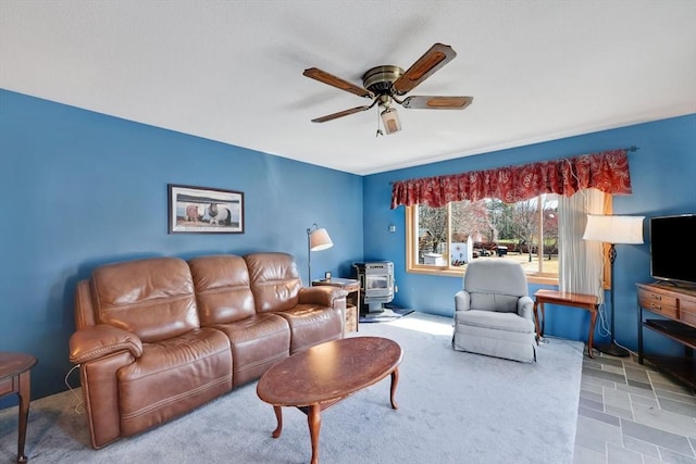 living room featuring a ceiling fan and a wood stove