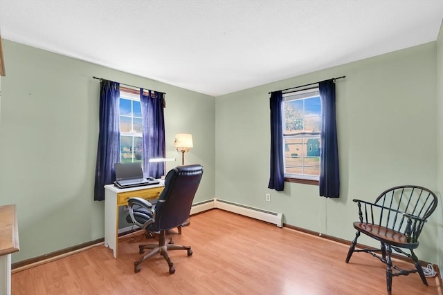 office space with a baseboard radiator, wood finished floors, a wealth of natural light, and baseboards