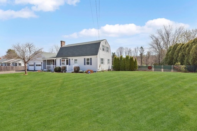 view of front facade featuring a porch, a gambrel roof, a front lawn, and fence