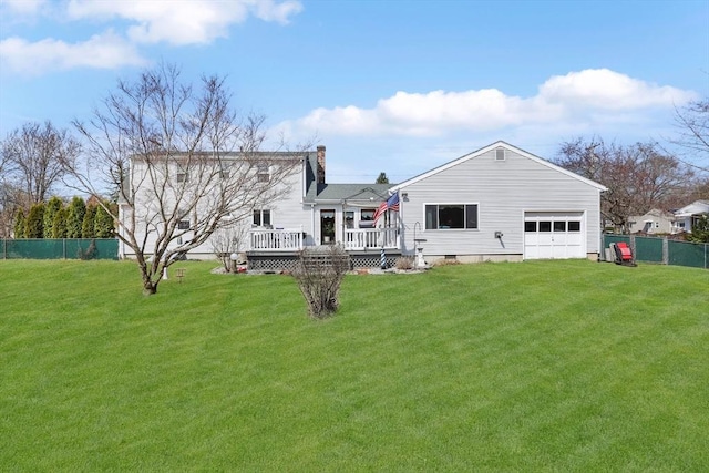 rear view of property with a chimney, fence, a wooden deck, an attached garage, and a lawn