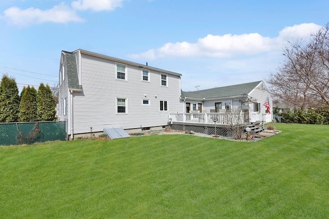 back of house featuring fence, a wooden deck, and a lawn