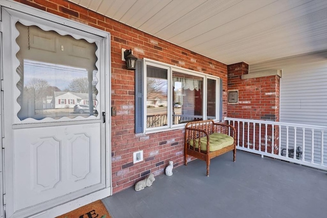 property entrance with covered porch and brick siding