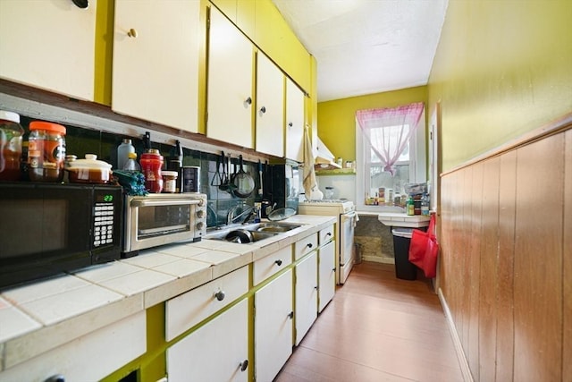 kitchen with white cabinetry, sink, tile counters, and white gas stove