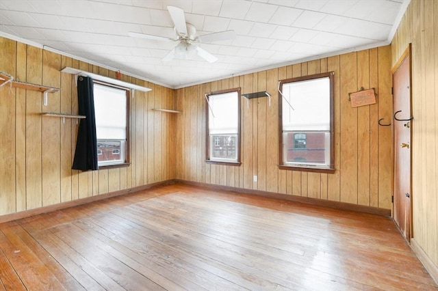 unfurnished room with ceiling fan, ornamental molding, wooden walls, and light hardwood / wood-style floors