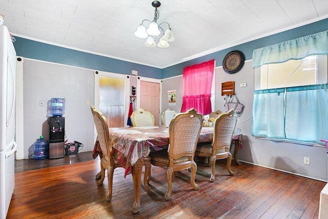 dining area featuring ornamental molding, wood-type flooring, and a notable chandelier