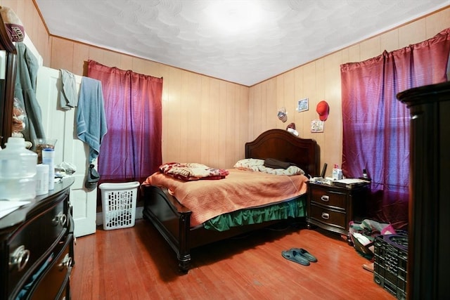 bedroom with hardwood / wood-style floors and wood walls